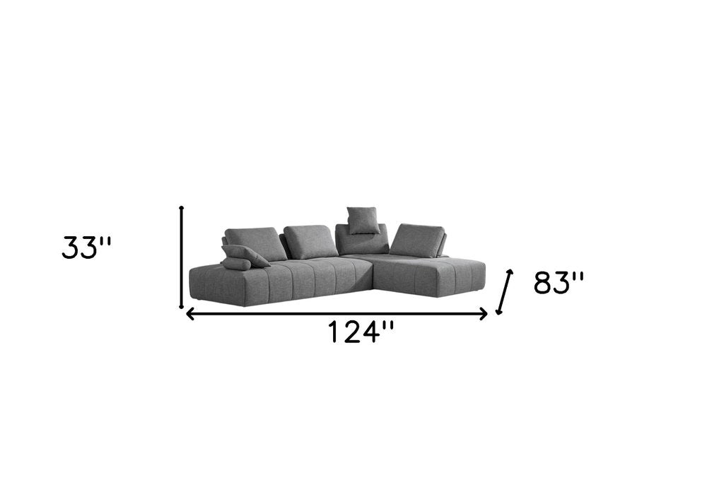 Sofá modular en forma de L de dos piezas de poliéster gris con chaise longue y cojines.