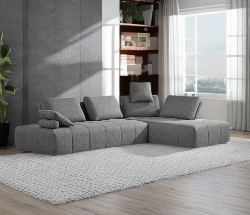 Sofá modular en forma de L de dos piezas de poliéster gris con chaise longue y cojines.