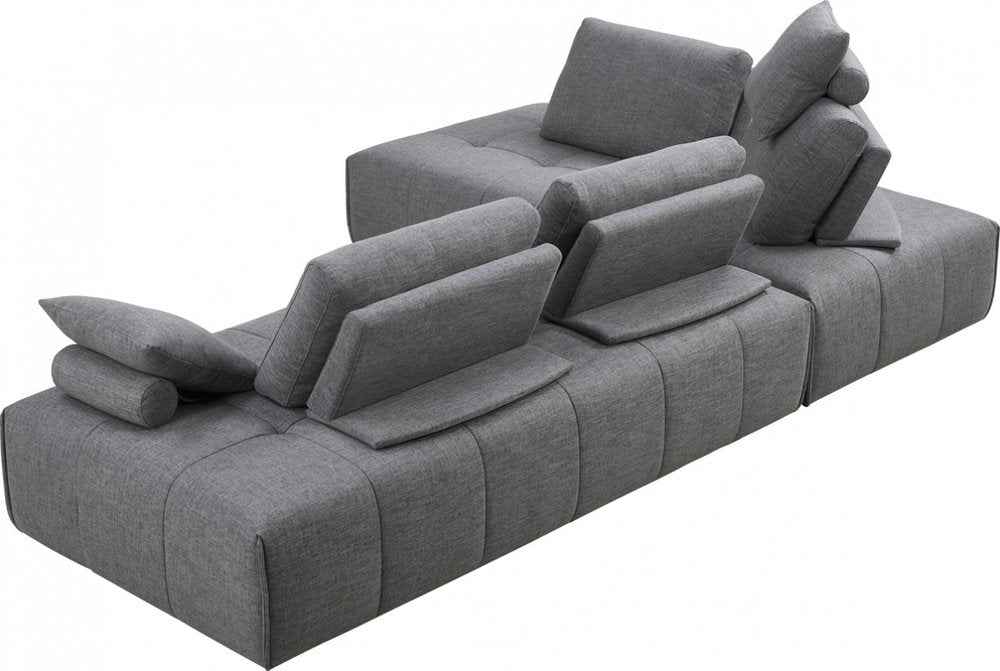 Sofá modular en forma de L de dos piezas de poliéster gris con chaise longue y cojines.