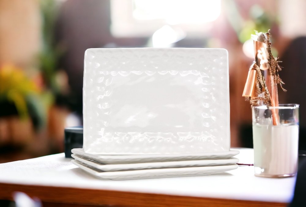 Juego de seis platos llanos de porcelana blanca con diseño de guijarros rectangulares.