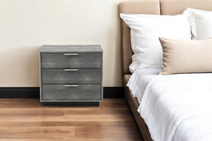 Mesita de noche de tres cajones de 22" de madera maciza y manufacturada de color gris.