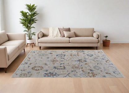 9' X 13' Ivory Blue and Gold Floral Power Loom Worn Faded Area Rug With Fringe